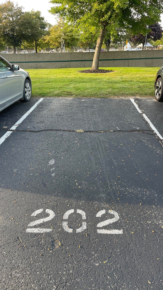 view of parking / parking lot featuring a lawn