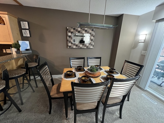 carpeted dining room with a textured ceiling