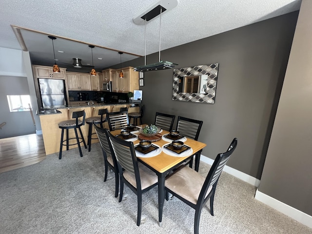 carpeted dining room featuring a textured ceiling