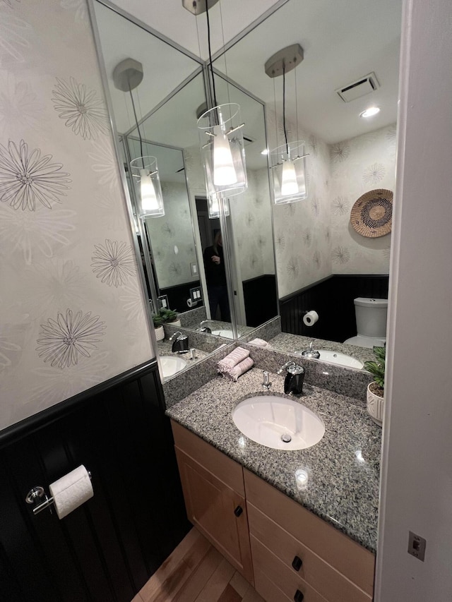 bathroom with toilet, vanity, and hardwood / wood-style flooring