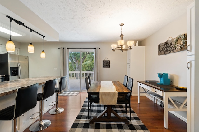 dining area featuring a textured ceiling, an inviting chandelier, and dark hardwood / wood-style floors