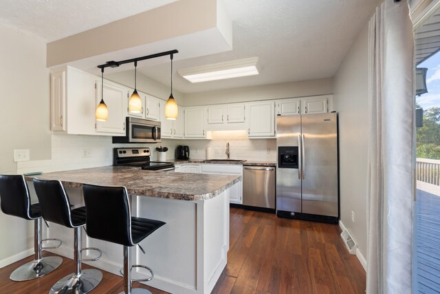 kitchen featuring white cabinets, kitchen peninsula, appliances with stainless steel finishes, and sink