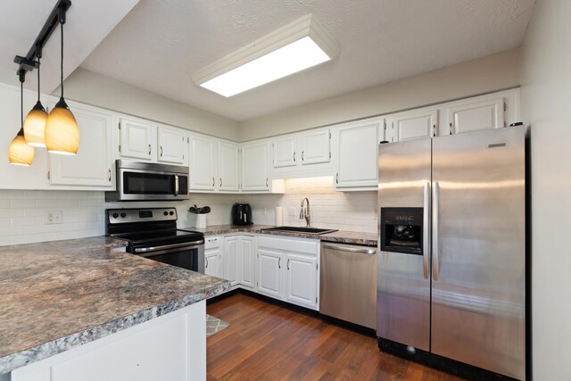 kitchen with appliances with stainless steel finishes, hanging light fixtures, dark hardwood / wood-style floors, and white cabinetry