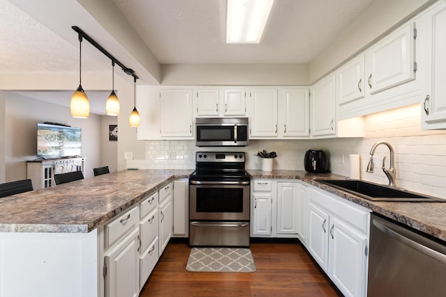 kitchen featuring dark hardwood / wood-style floors, sink, white cabinetry, kitchen peninsula, and stainless steel appliances