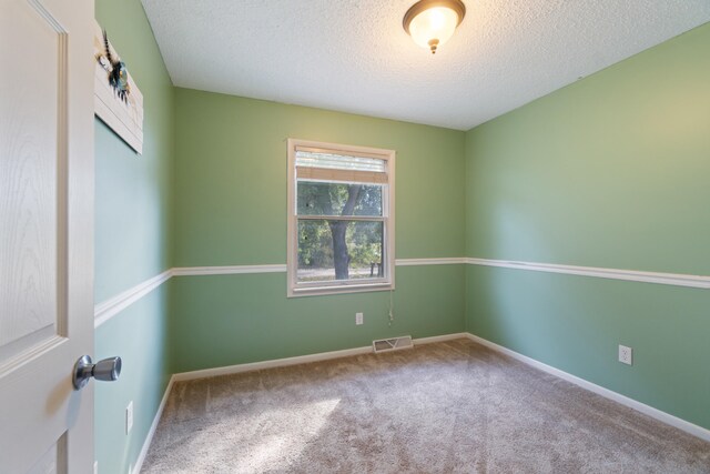 empty room featuring a textured ceiling and carpet