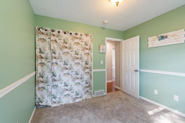 carpeted spare room with a textured ceiling