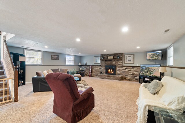 living room featuring a textured ceiling, a fireplace, and light colored carpet