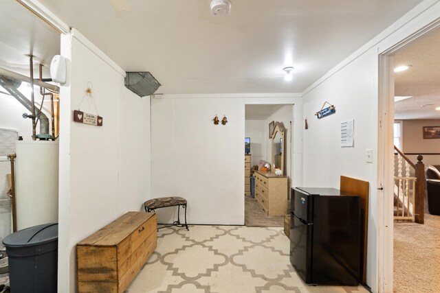 hall with ornamental molding, light colored carpet, and gas water heater