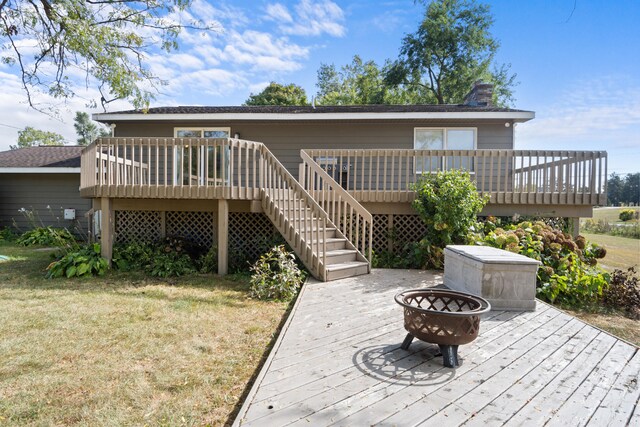 rear view of house featuring a wooden deck, a yard, and a fire pit