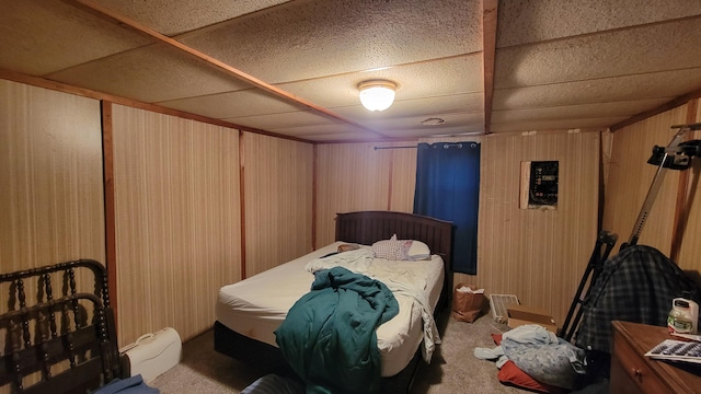 bedroom with carpet flooring, a paneled ceiling, and wooden walls