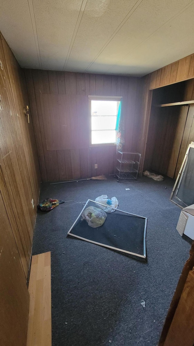 unfurnished bedroom with a textured ceiling and wood walls