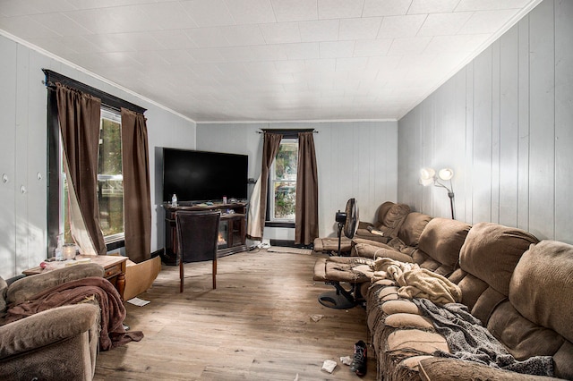 living room featuring light hardwood / wood-style flooring, wood walls, plenty of natural light, and crown molding