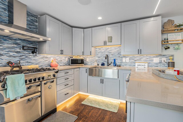 kitchen featuring wall chimney exhaust hood, backsplash, appliances with stainless steel finishes, and dark hardwood / wood-style floors