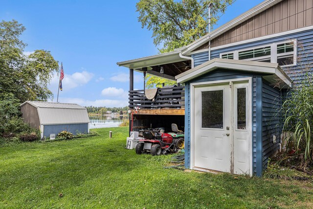 view of outbuilding with a lawn and a water view