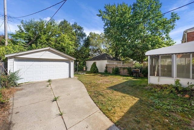 view of yard featuring a garage, a sunroom, and an outbuilding