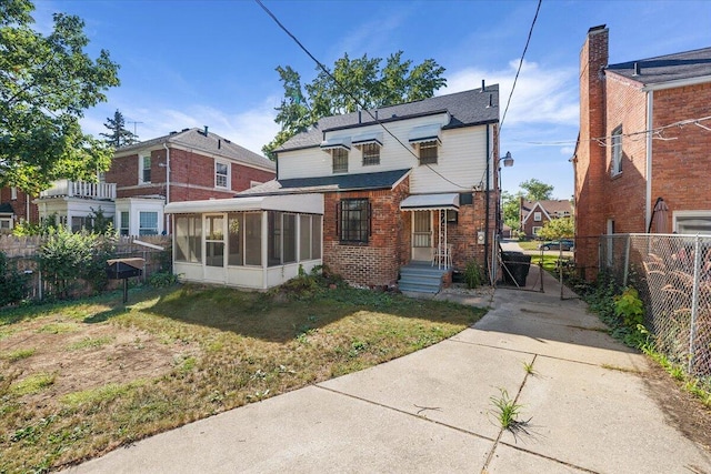 back of house featuring a sunroom and a lawn