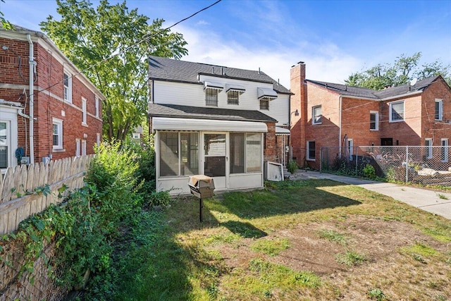 back of property featuring a sunroom and a lawn