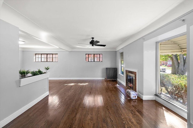 unfurnished living room featuring a wealth of natural light, ceiling fan, radiator, and dark hardwood / wood-style floors