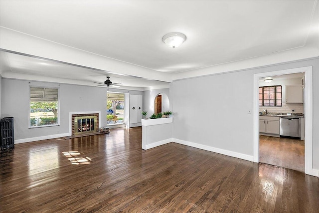 unfurnished living room with a fireplace, dark hardwood / wood-style flooring, and ceiling fan