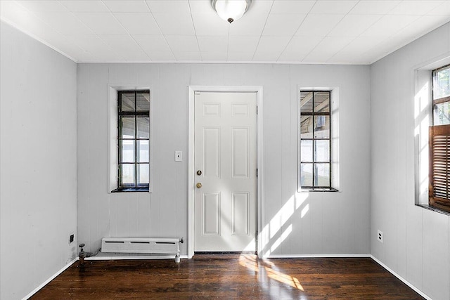 foyer entrance featuring wooden walls, baseboard heating, and dark hardwood / wood-style flooring