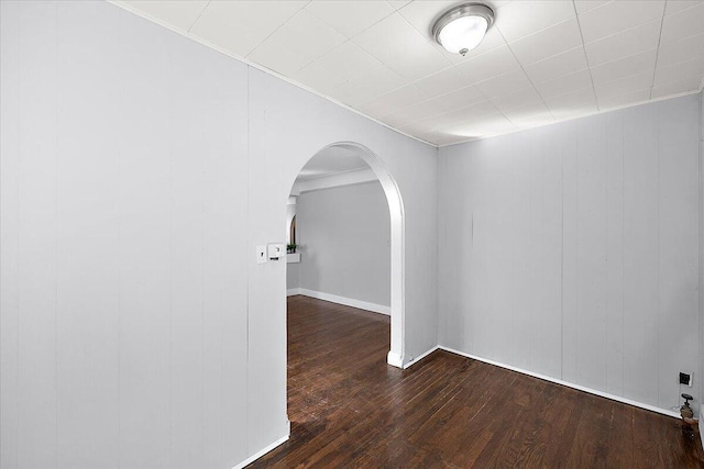 spare room featuring wood walls and dark wood-type flooring