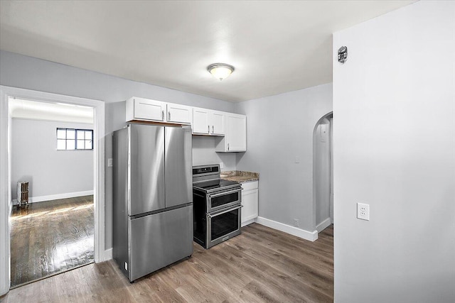 kitchen featuring wood-type flooring, stone countertops, stainless steel appliances, and white cabinets