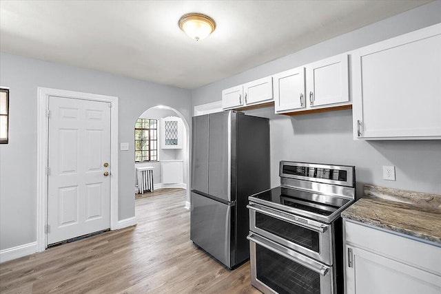 kitchen featuring dark stone counters, stainless steel appliances, white cabinetry, and light hardwood / wood-style floors