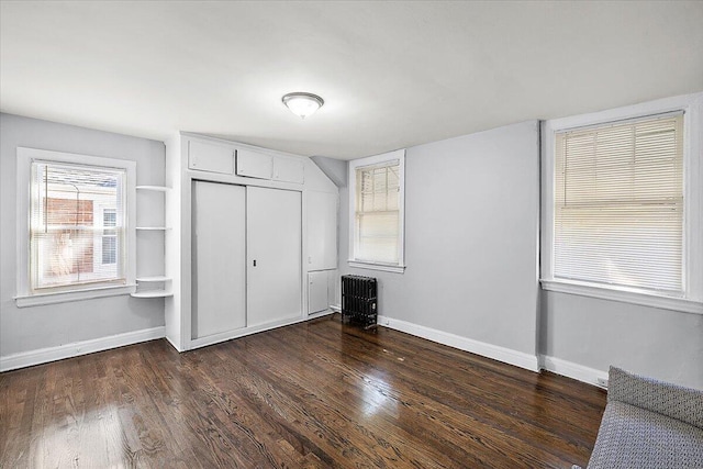 unfurnished bedroom featuring radiator, dark hardwood / wood-style flooring, and a closet