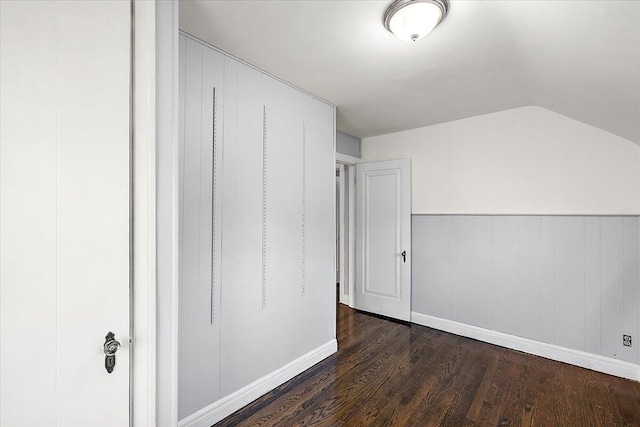 additional living space with wooden walls, vaulted ceiling, and dark hardwood / wood-style flooring