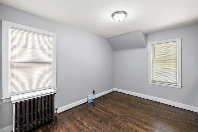 bonus room with radiator heating unit, a wealth of natural light, vaulted ceiling, and dark hardwood / wood-style floors