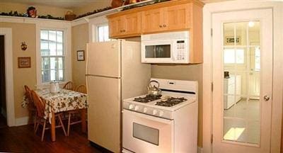 kitchen with white appliances, light brown cabinetry, and dark wood-type flooring