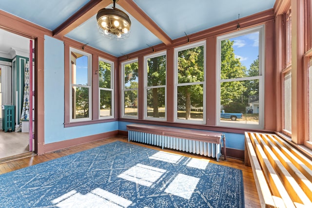 unfurnished sunroom with an inviting chandelier, beam ceiling, radiator heating unit, and a healthy amount of sunlight