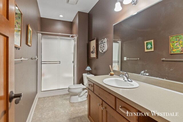 bathroom featuring tile patterned flooring, vanity, toilet, and a shower with shower door