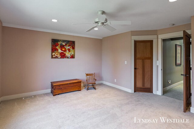 living area featuring ceiling fan, light colored carpet, and ornamental molding