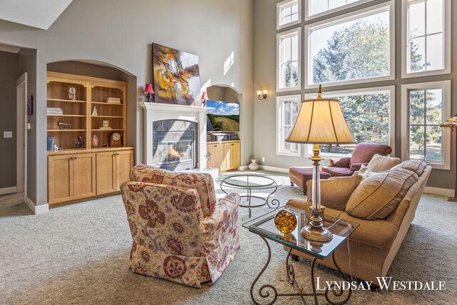 living room with a towering ceiling, light colored carpet, and plenty of natural light