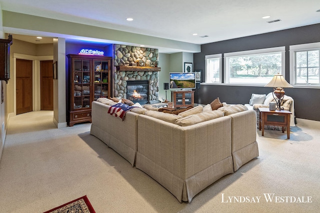 carpeted living room with a stone fireplace