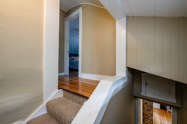 stairway featuring wooden walls, lofted ceiling, and hardwood / wood-style floors