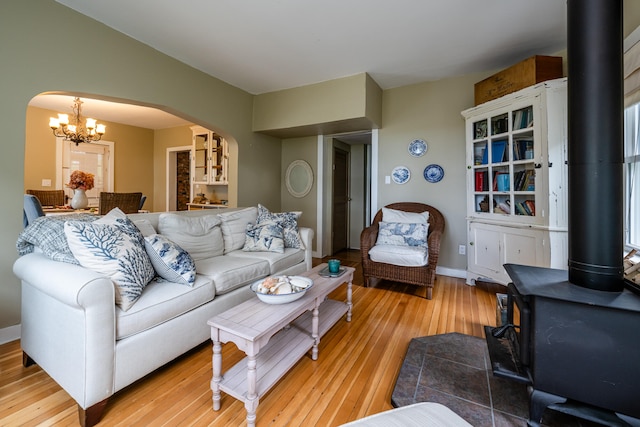 living room featuring a chandelier, light hardwood / wood-style floors, and a wood stove