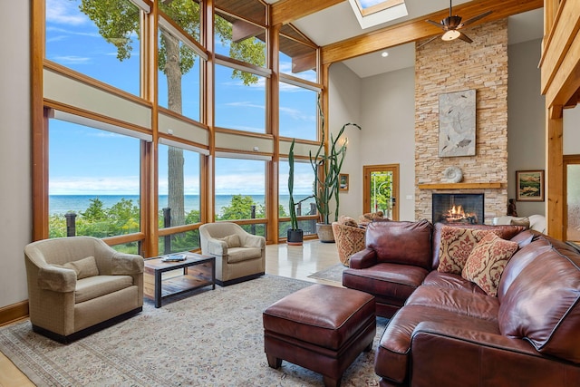 living room with a skylight, a fireplace, a high ceiling, and a water view