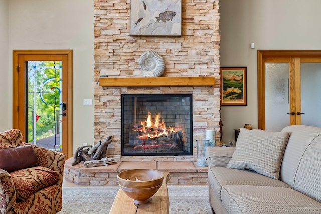 living room with a stone fireplace and a towering ceiling