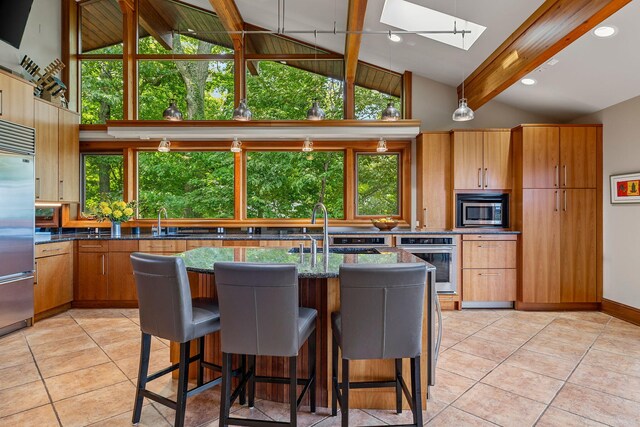 kitchen featuring a skylight, built in appliances, beam ceiling, and sink