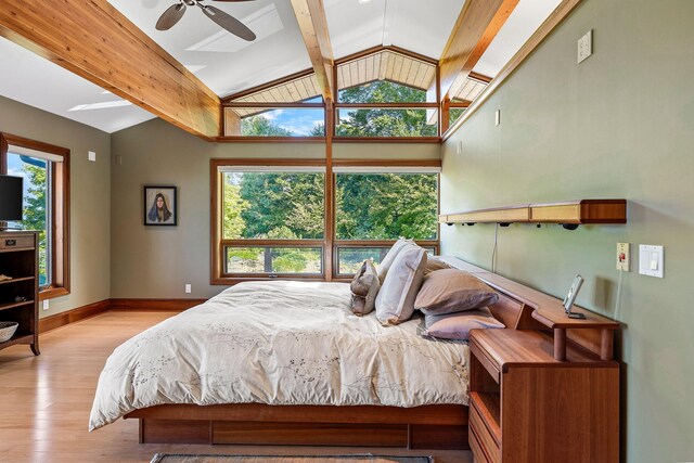 bedroom with ceiling fan, vaulted ceiling with beams, light hardwood / wood-style floors, and multiple windows