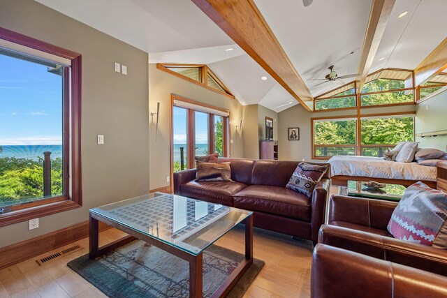 living room with vaulted ceiling with beams, a water view, light hardwood / wood-style floors, and ceiling fan