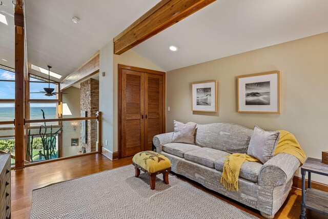 living room featuring lofted ceiling with beams, light hardwood / wood-style floors, and a water view