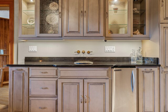 kitchen featuring dark stone countertops and stainless steel fridge