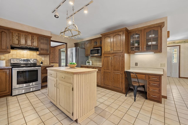 kitchen featuring tasteful backsplash, a notable chandelier, a kitchen island, stainless steel appliances, and light tile patterned floors