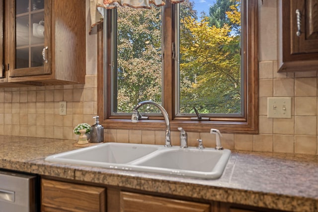 kitchen with light stone countertops, stainless steel dishwasher, and sink