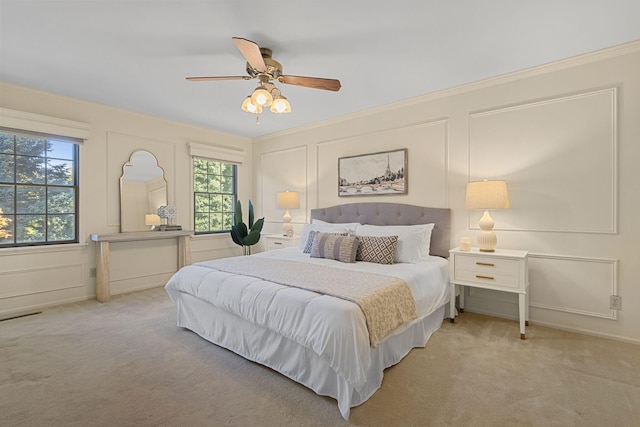 carpeted bedroom with ornamental molding and ceiling fan