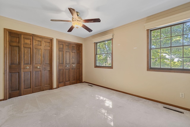 unfurnished bedroom featuring carpet, multiple windows, and ceiling fan