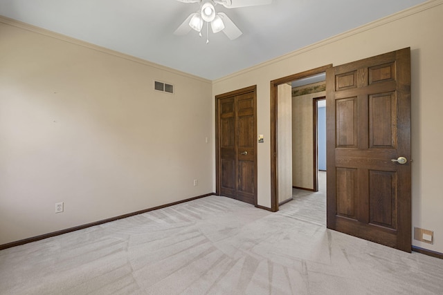 unfurnished bedroom with ornamental molding, light carpet, ceiling fan, and a closet